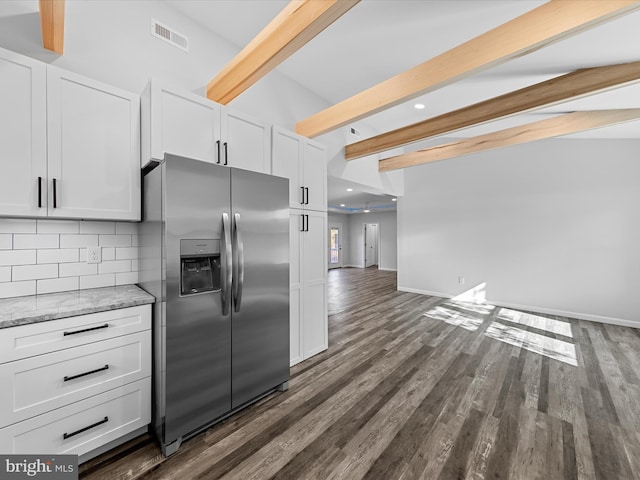 kitchen featuring beam ceiling, white cabinetry, light stone counters, stainless steel refrigerator with ice dispenser, and backsplash