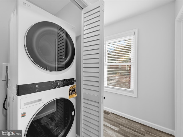 clothes washing area featuring stacked washer / dryer and wood-type flooring