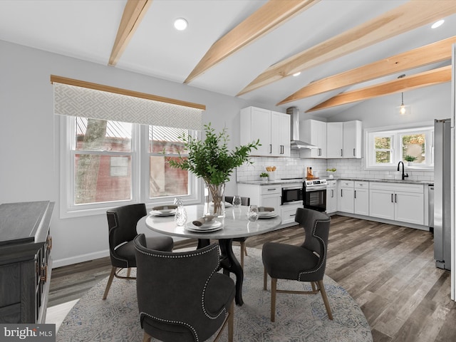 dining room featuring dark hardwood / wood-style flooring, lofted ceiling with beams, and sink