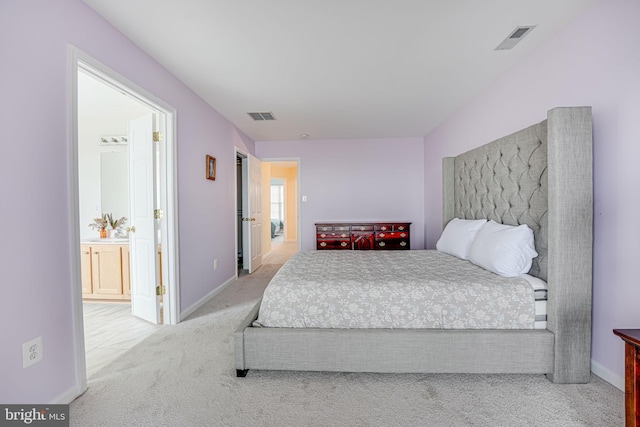 bedroom featuring ensuite bathroom and light colored carpet