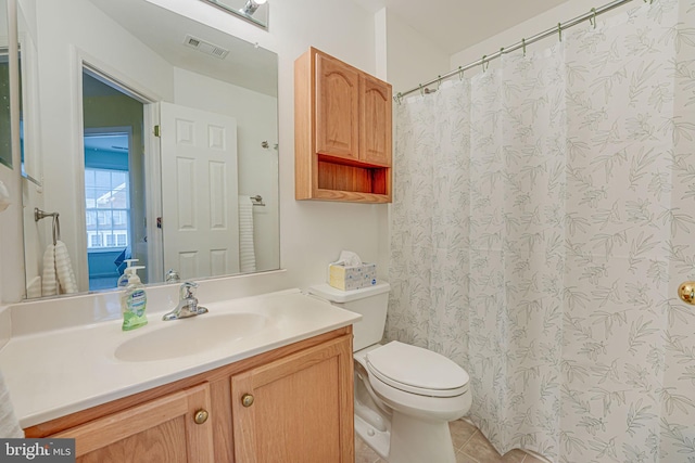 bathroom with toilet, vanity, and tile patterned floors