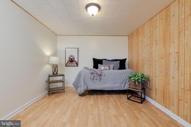 bedroom with light hardwood / wood-style floors and wood walls