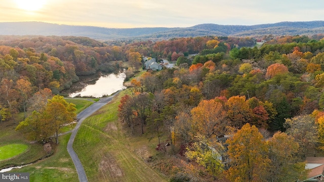 aerial view at dusk featuring a water and mountain view