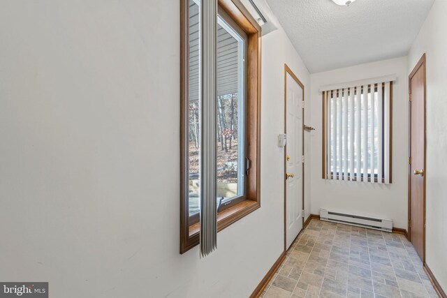 doorway to outside featuring plenty of natural light, a textured ceiling, and a baseboard heating unit