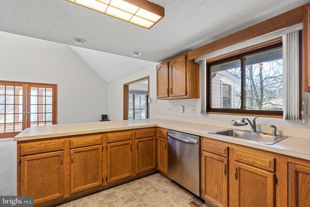 kitchen featuring kitchen peninsula, a textured ceiling, vaulted ceiling, sink, and dishwasher