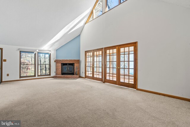 unfurnished living room with french doors, carpet floors, high vaulted ceiling, and a brick fireplace