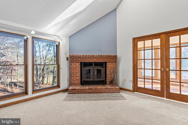 unfurnished living room featuring light carpet, french doors, a textured ceiling, and a brick fireplace