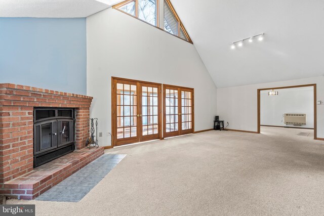 unfurnished living room with rail lighting, high vaulted ceiling, heating unit, light carpet, and a fireplace