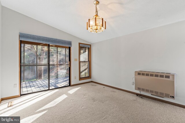 empty room featuring radiator heating unit, vaulted ceiling, a notable chandelier, carpet floors, and heating unit