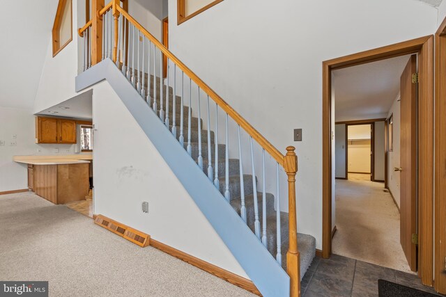 stairway with carpet flooring and a towering ceiling