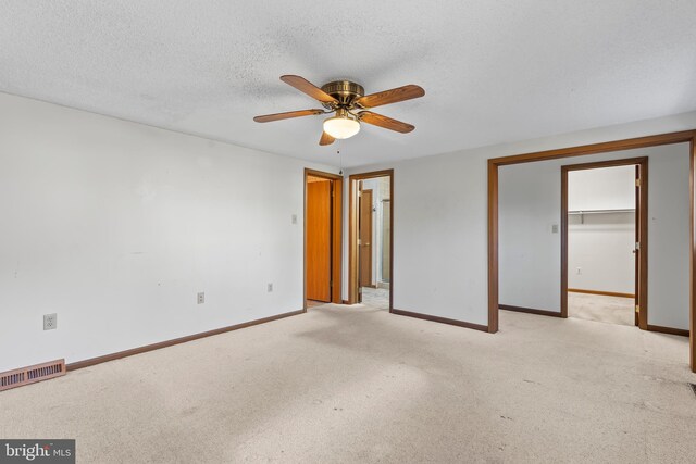 empty room featuring ceiling fan, light colored carpet, and a textured ceiling