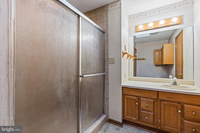 bathroom featuring vanity, a textured ceiling, and walk in shower