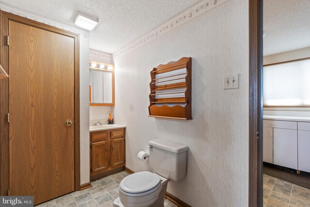 bathroom featuring vanity, a textured ceiling, and toilet