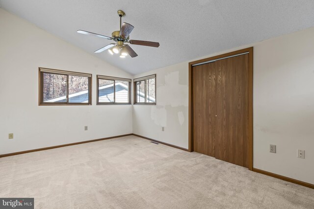 unfurnished bedroom featuring ceiling fan, vaulted ceiling, light carpet, and multiple windows