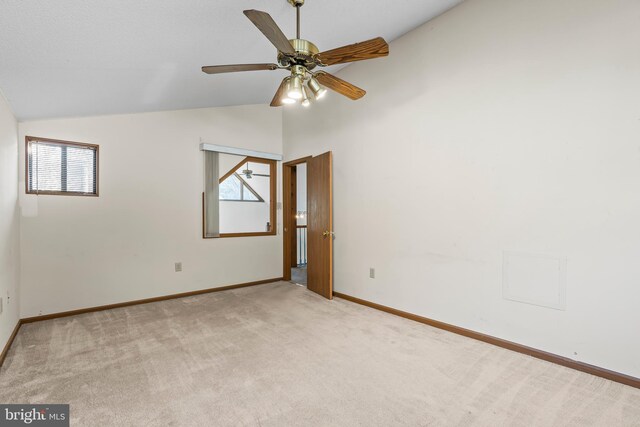 carpeted empty room with vaulted ceiling, ceiling fan, and a healthy amount of sunlight