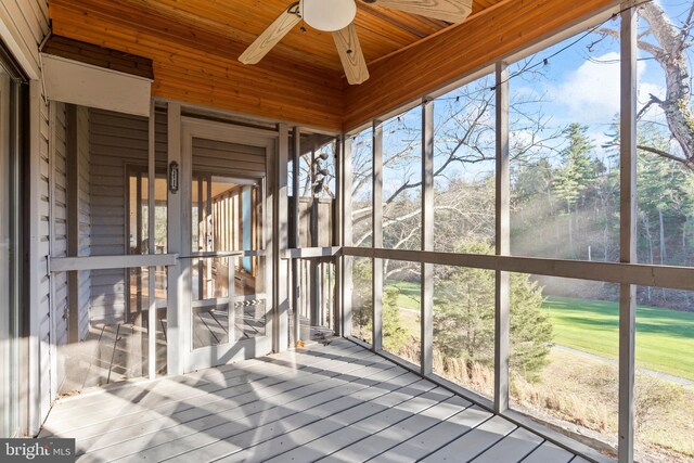 unfurnished sunroom featuring ceiling fan, a healthy amount of sunlight, and wooden ceiling