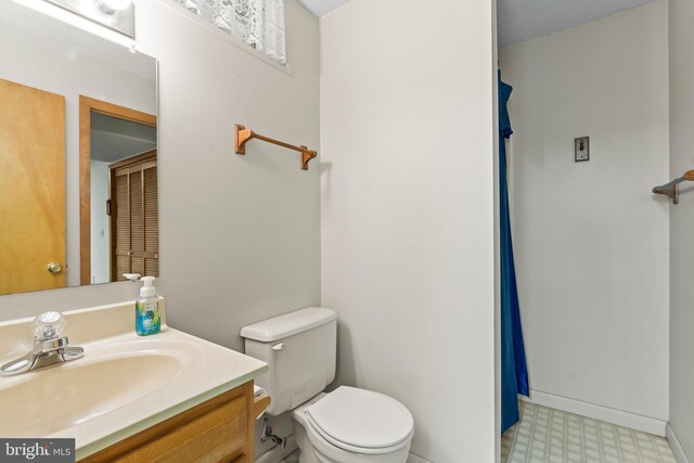 bathroom featuring a textured ceiling, vanity, and toilet