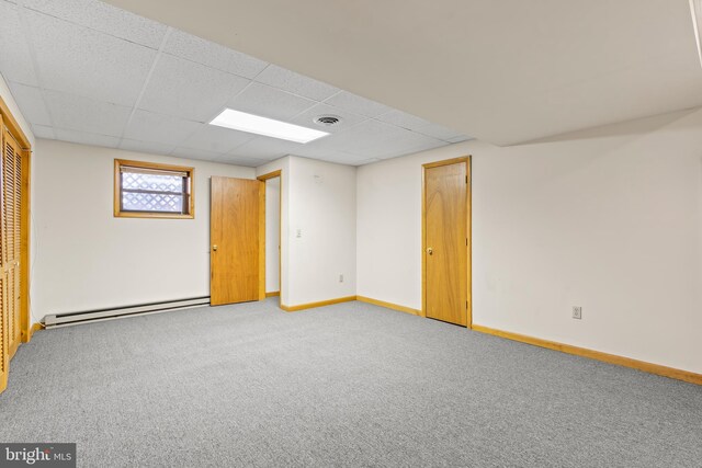 basement featuring a paneled ceiling, carpet floors, and baseboard heating