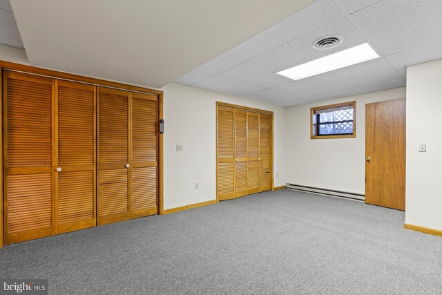 unfurnished bedroom with a paneled ceiling, carpet, and a baseboard heating unit