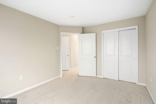 unfurnished bedroom with light colored carpet and a closet