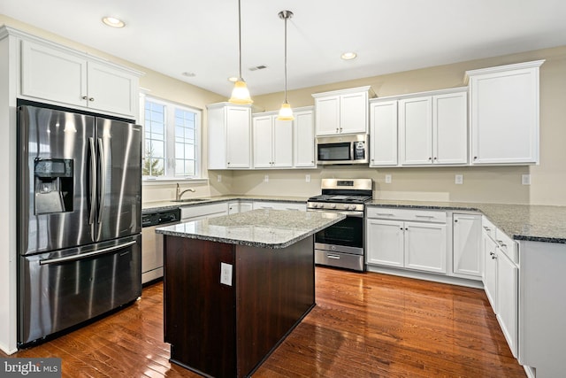 kitchen with decorative light fixtures, dark hardwood / wood-style flooring, light stone countertops, and stainless steel appliances