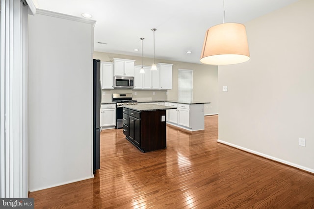 kitchen featuring a center island, hanging light fixtures, stainless steel appliances, white cabinets, and hardwood / wood-style flooring