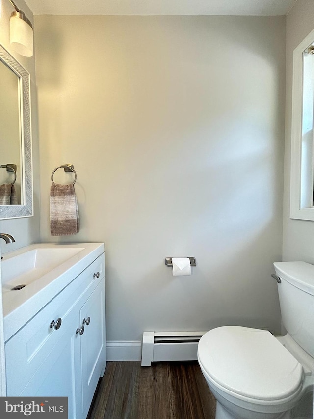 bathroom with vanity, hardwood / wood-style floors, a baseboard heating unit, and toilet