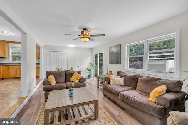 living room featuring light hardwood / wood-style flooring, cooling unit, and ceiling fan