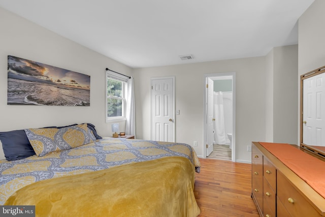 bedroom with ensuite bath and light wood-type flooring