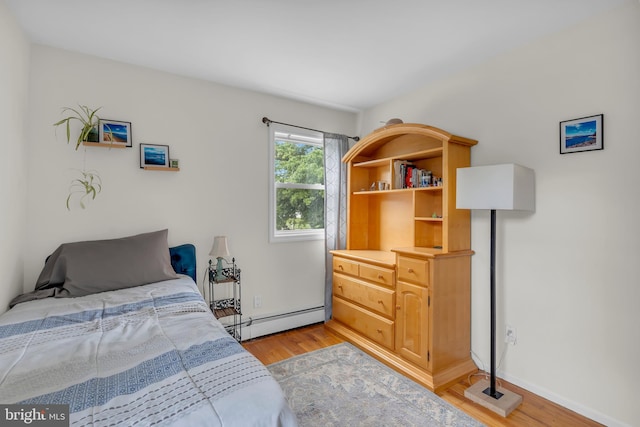 bedroom with light hardwood / wood-style flooring and baseboard heating