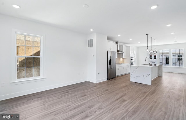 10812 Willow Ter, Fairfax, VA 22030 - kitchen with stainless steel fridge, wall chimney exhaust hood, a sink, light wood finished floors, and a center island with sink