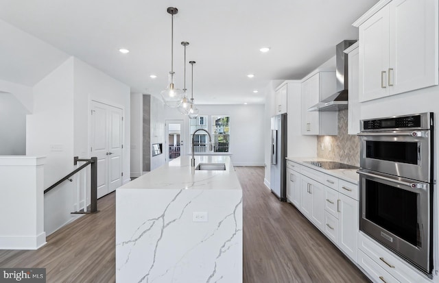 10812 Willow Ter, Fairfax, VA 22030 - kitchen featuring appliances with stainless steel finishes, wall chimney range hood, a sink, a center island with sink, and decorative backsplash