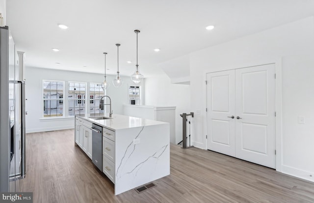 10812 Willow Ter, Fairfax, VA 22030 - kitchen featuring a sink, a center island with sink, light wood finished floors, stainless steel dishwasher, and white cabinets