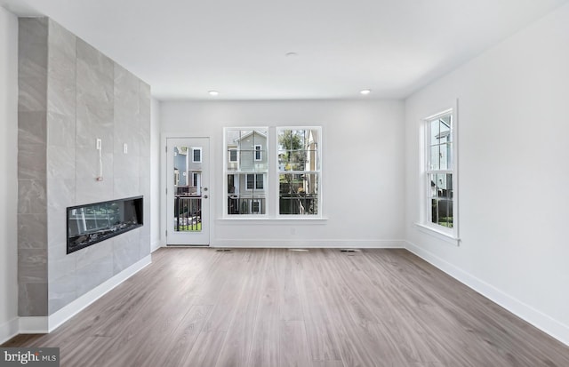 10812 Willow Ter, Fairfax, VA 22030 - unfurnished living room featuring wood finished floors, a tiled fireplace, baseboards, and recessed lighting