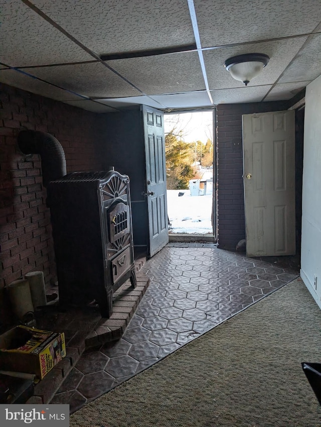 foyer featuring a wood stove, carpet flooring, and a drop ceiling