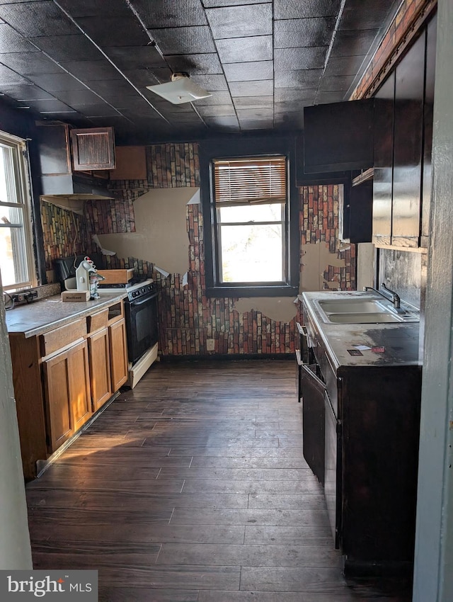 kitchen with a sink, dark wood-style flooring, light countertops, a paneled ceiling, and electric stove