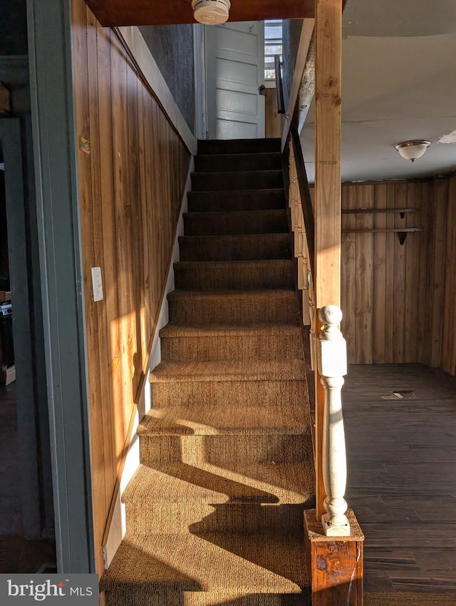stairway featuring wood walls and wood finished floors