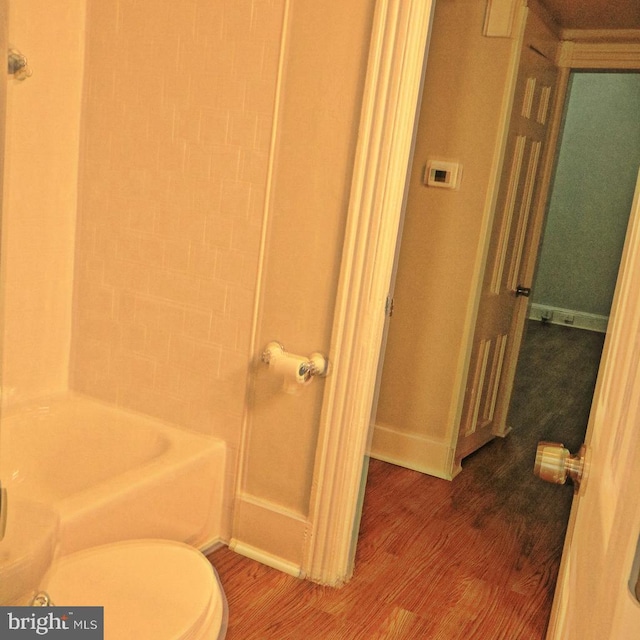 bathroom with tiled shower / bath, hardwood / wood-style flooring, and toilet