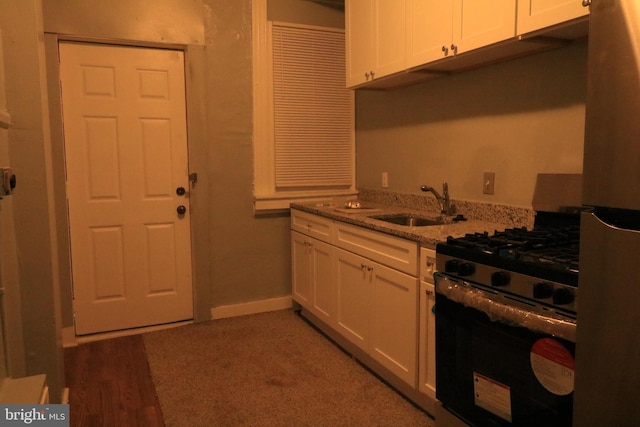 kitchen with light stone counters, range with gas cooktop, sink, white cabinets, and refrigerator