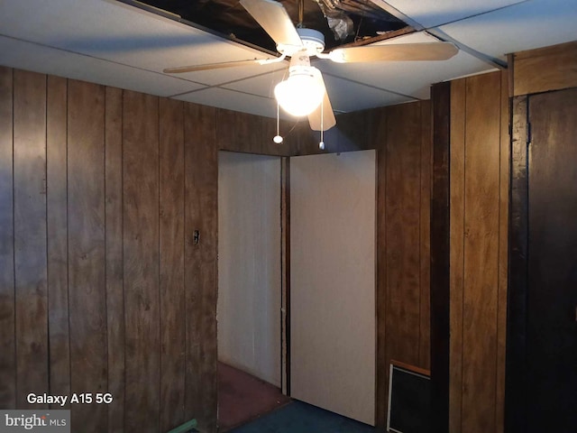 interior space with wood walls and ceiling fan