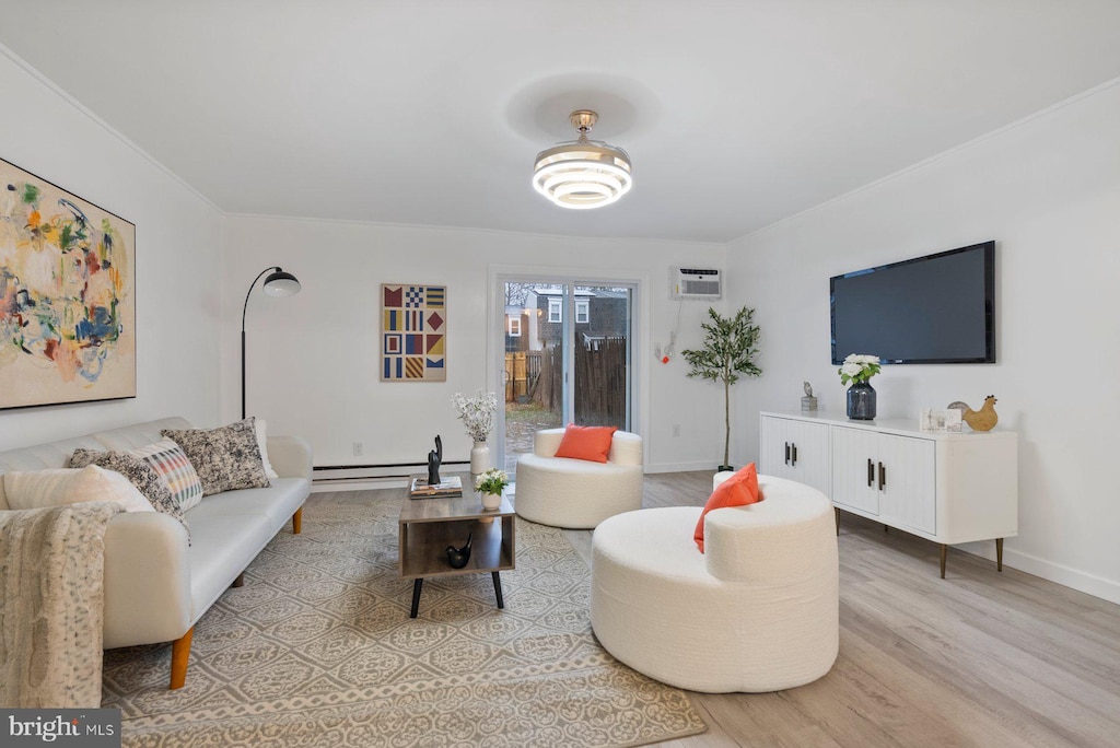 living area featuring a wall unit AC, ornamental molding, baseboards, and light wood-type flooring