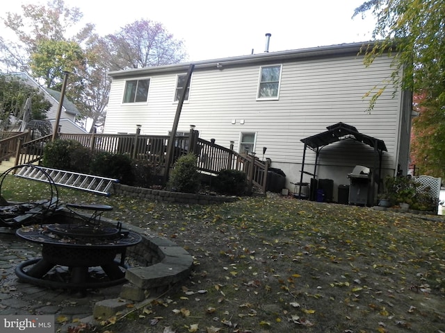 rear view of property with a wooden deck and a fire pit