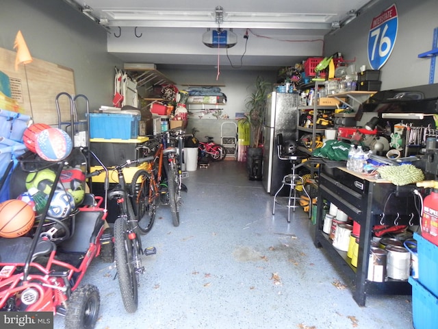 garage with a garage door opener and stainless steel refrigerator