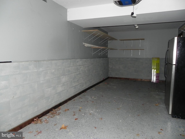 garage featuring a garage door opener and stainless steel refrigerator