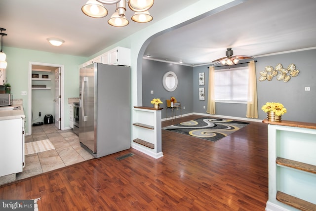 kitchen with white cabinets, decorative light fixtures, appliances with stainless steel finishes, and light hardwood / wood-style flooring