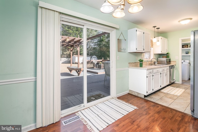 kitchen featuring hanging light fixtures, light wood-type flooring, a notable chandelier, white cabinetry, and stainless steel appliances