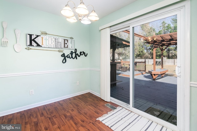 entryway with dark wood-type flooring and an inviting chandelier