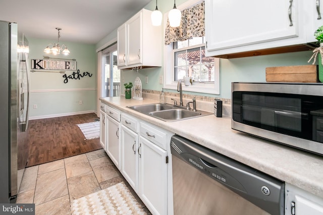 kitchen featuring decorative light fixtures, white cabinetry, stainless steel appliances, and a wealth of natural light