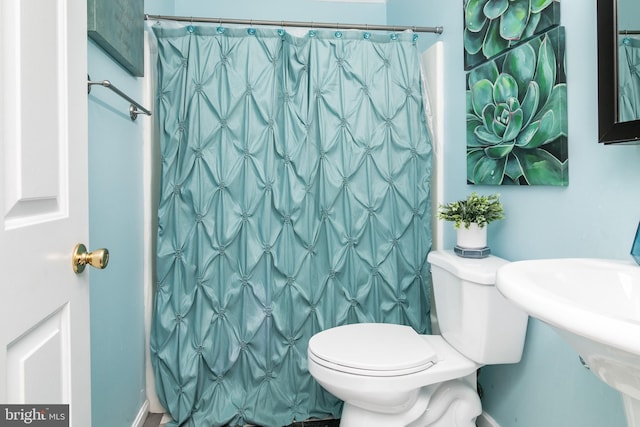 bathroom featuring a shower with shower curtain and toilet