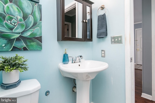 bathroom with hardwood / wood-style flooring, toilet, and ornamental molding